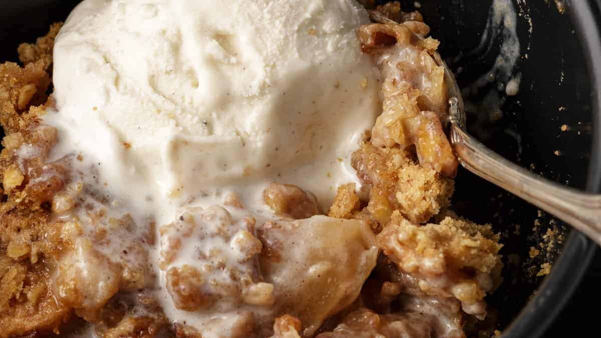 A spoon full of apple crisp with ice cream