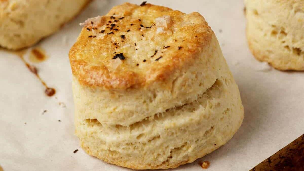 A tall and fluffy biscuit on a baking sheet.