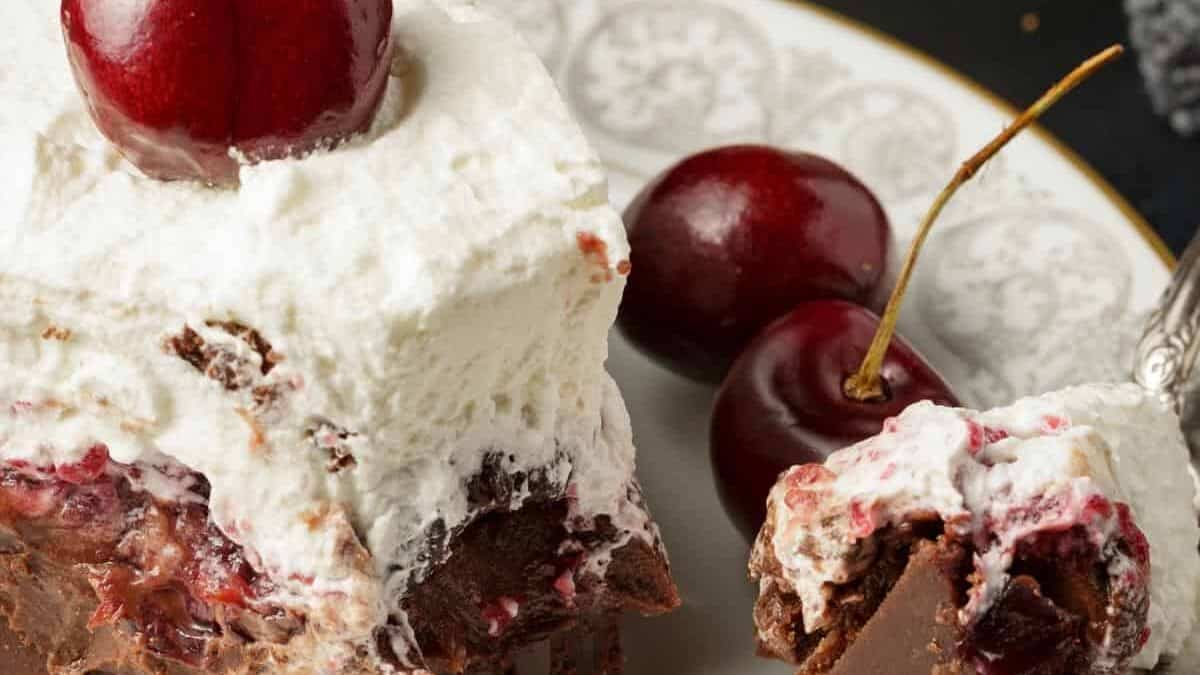 A bite of chocolate pie with cherries on t plate.