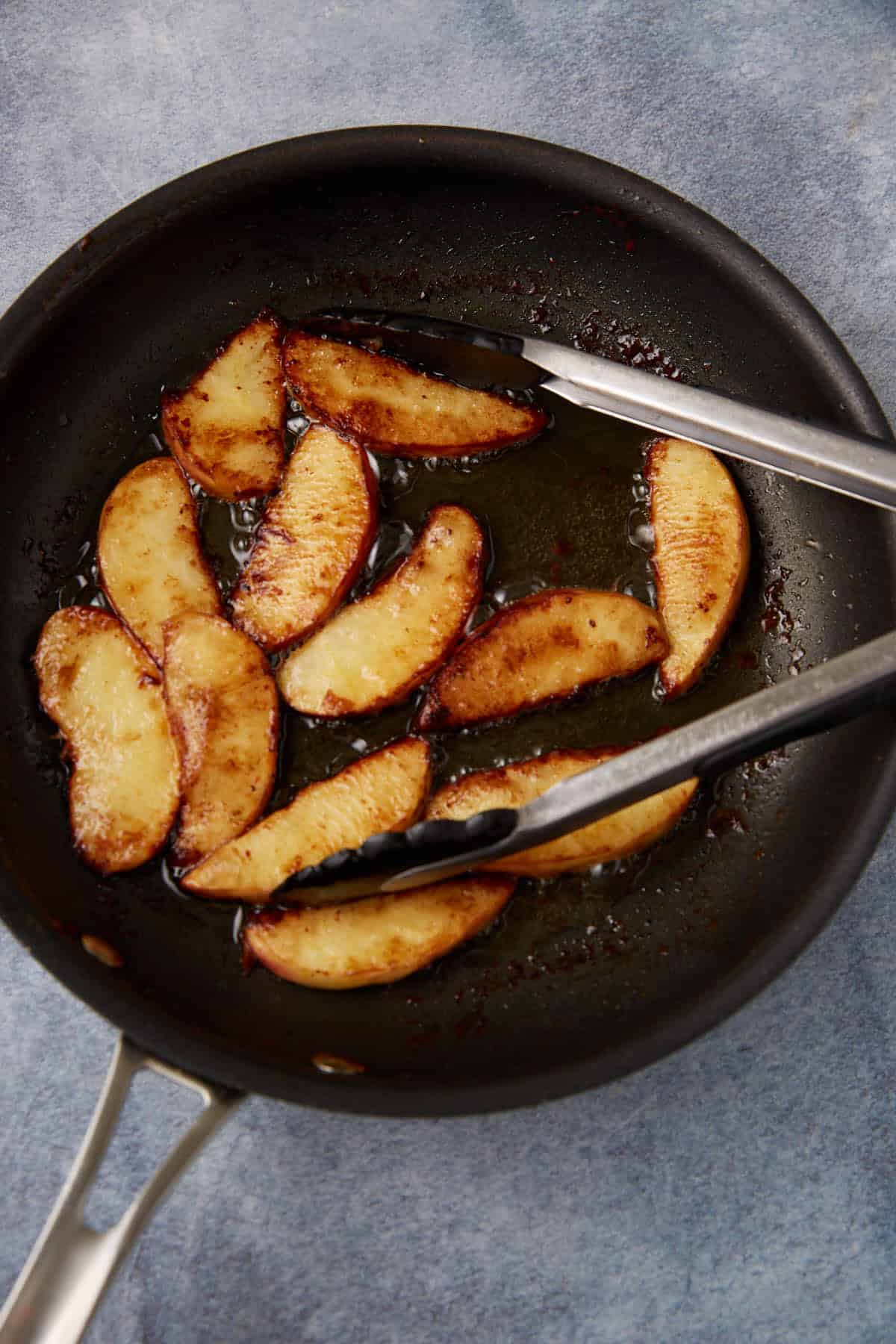 Apples cooked in butter in a skillet.