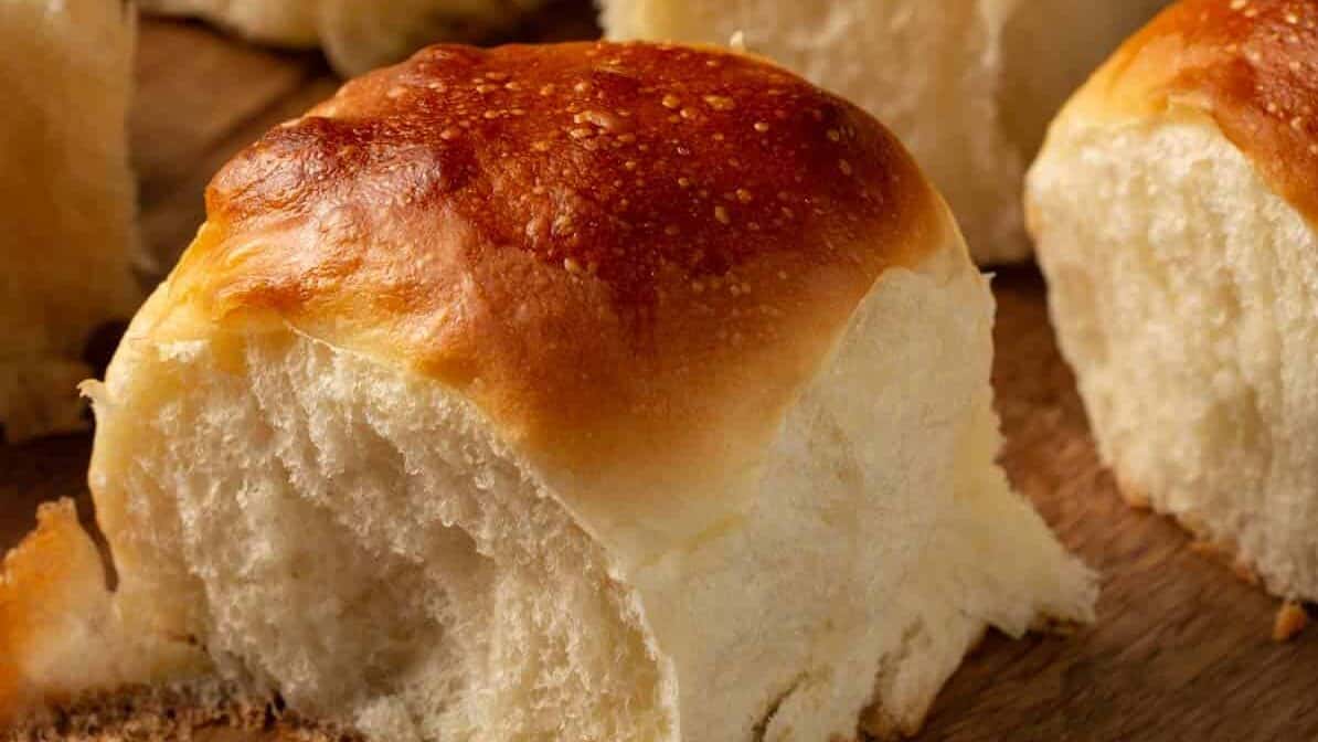 Individual challah buns on a wooden board.