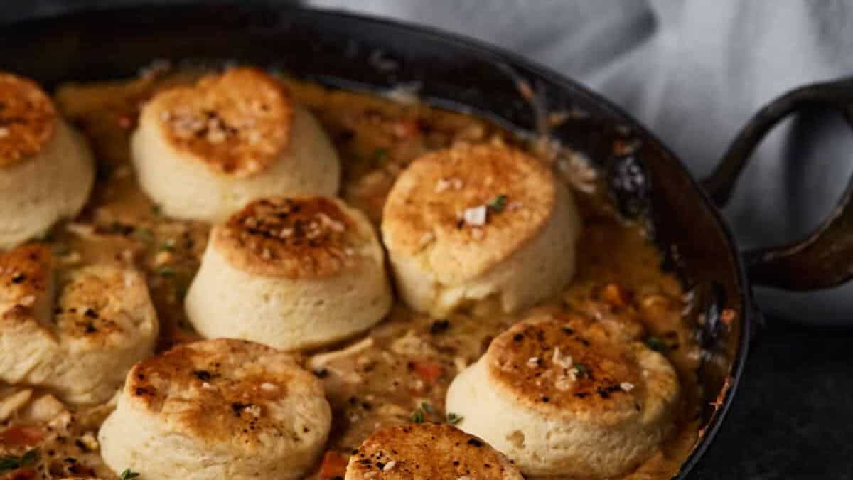 Biscuits on top of chicken pot pie in a skillet.