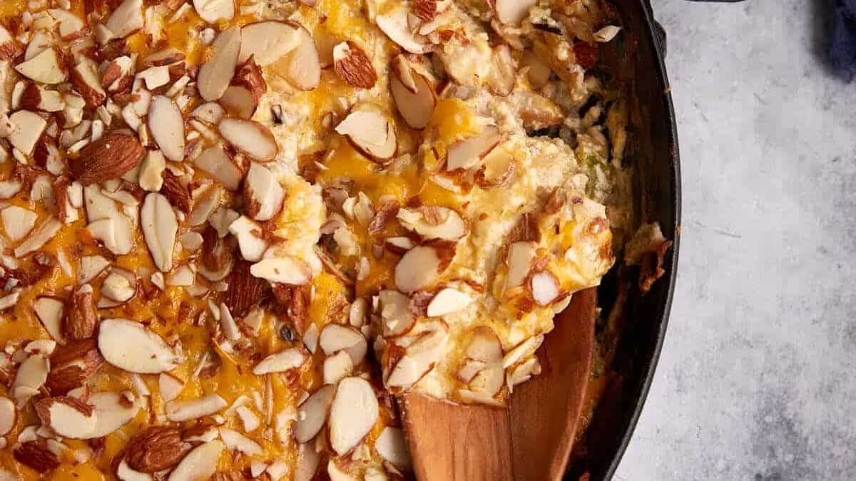 A skillet of chicken and wild rice casserole with a wooden spoon.