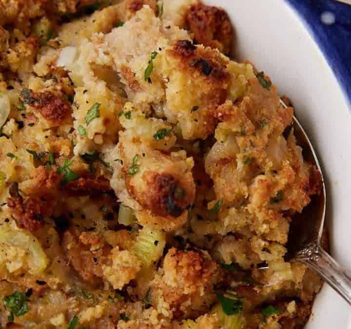 A serving spoon in a casserole dish of cornbread dressing.