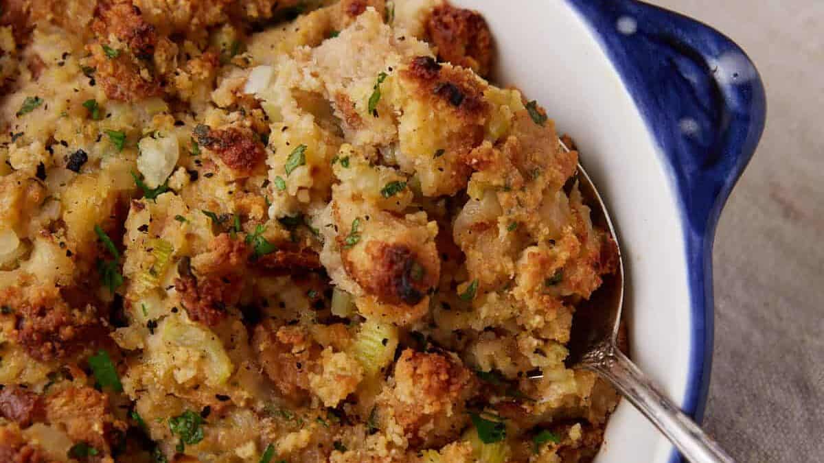 A serving spoon in a casserole dish of cornbread dressing.
