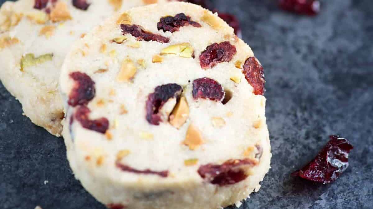 Pistachio and cranberry shortbread cookies on a black background.