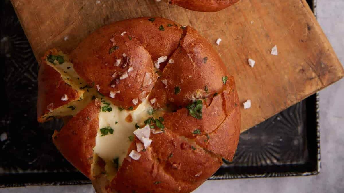 Two garlic rolls filled with cream cheese next to flaky salt.