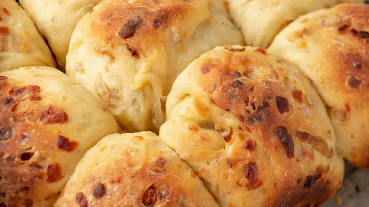 A batch of onion rolls on a wire rack.