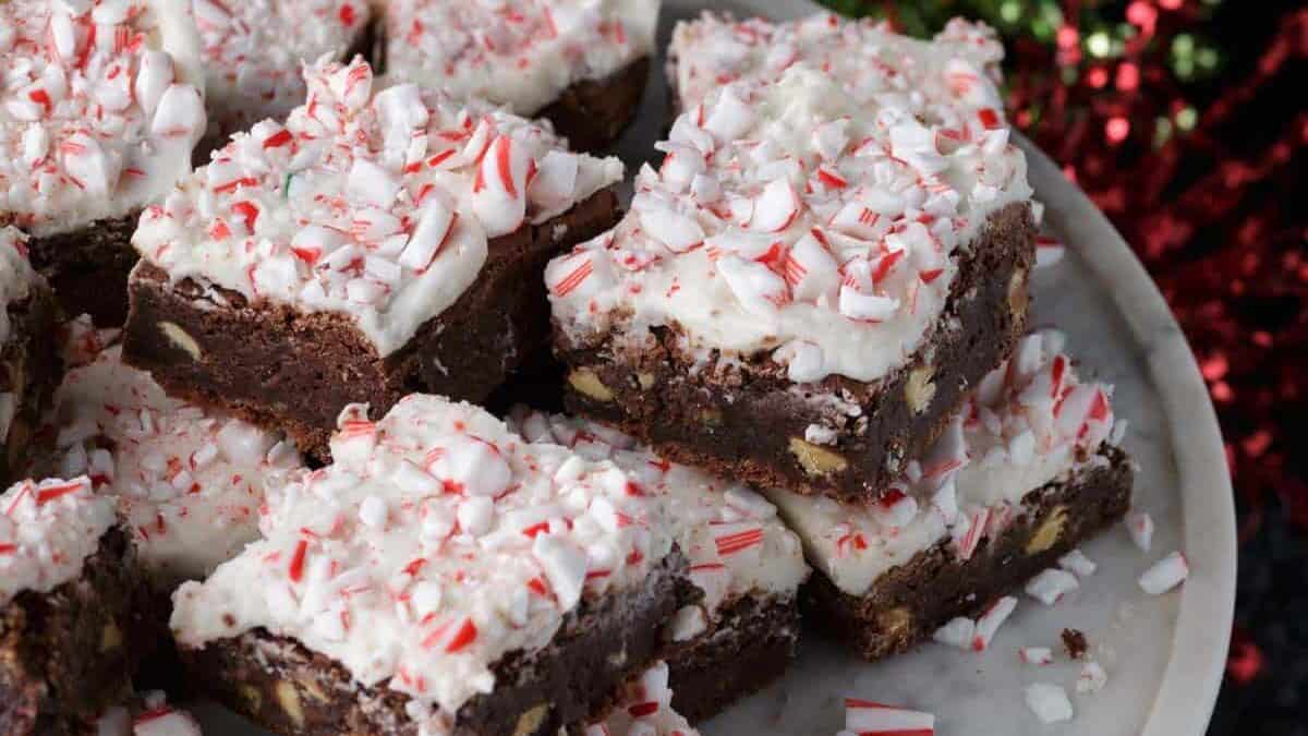 Frosted peppermint brownies stacked on a marble platter.
