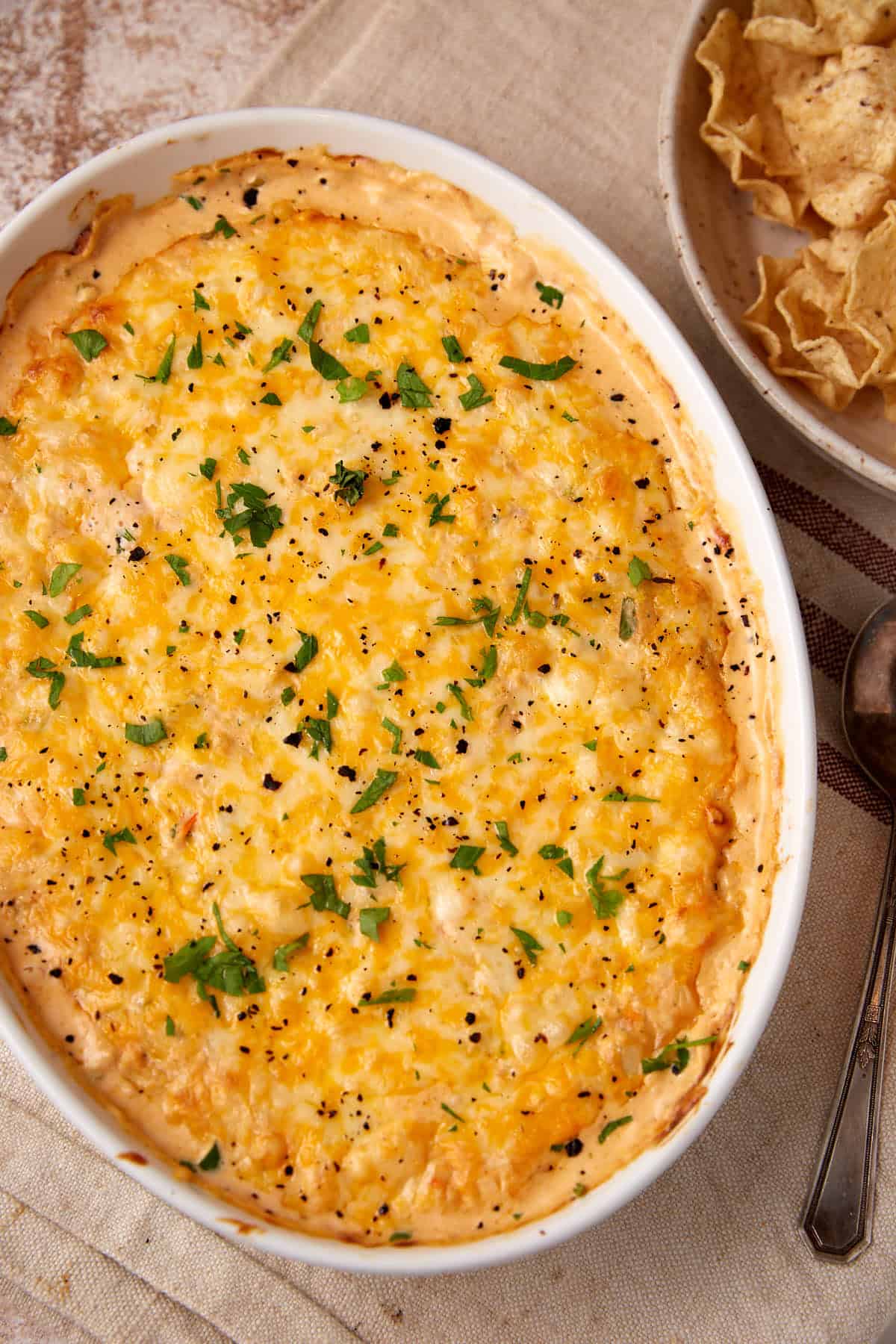 A baked seafood dip next to corn chips.