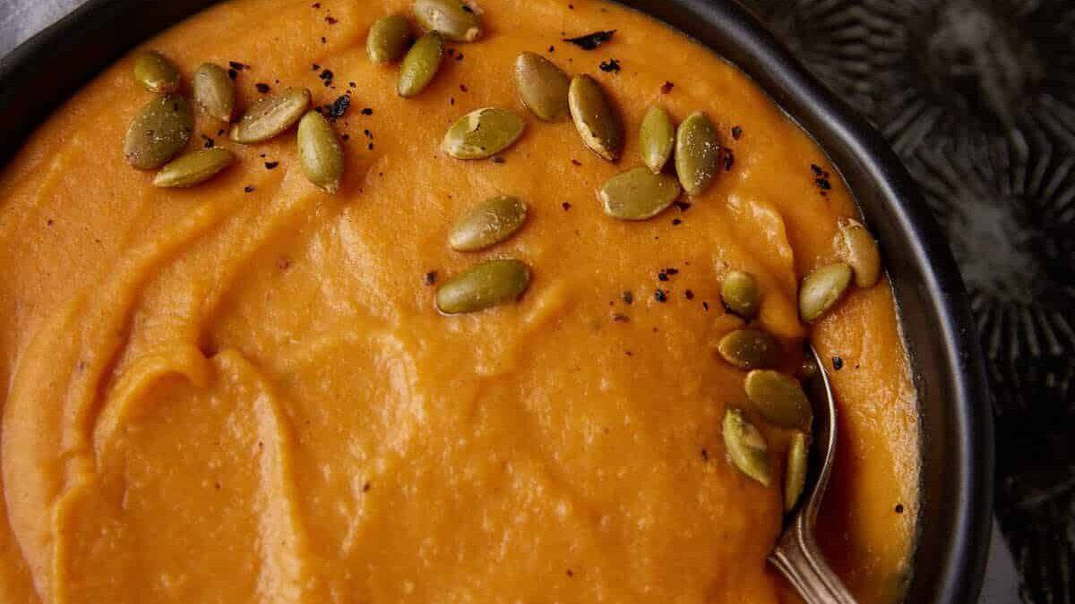 A bowl of sweet potato soup with a spoon in it.