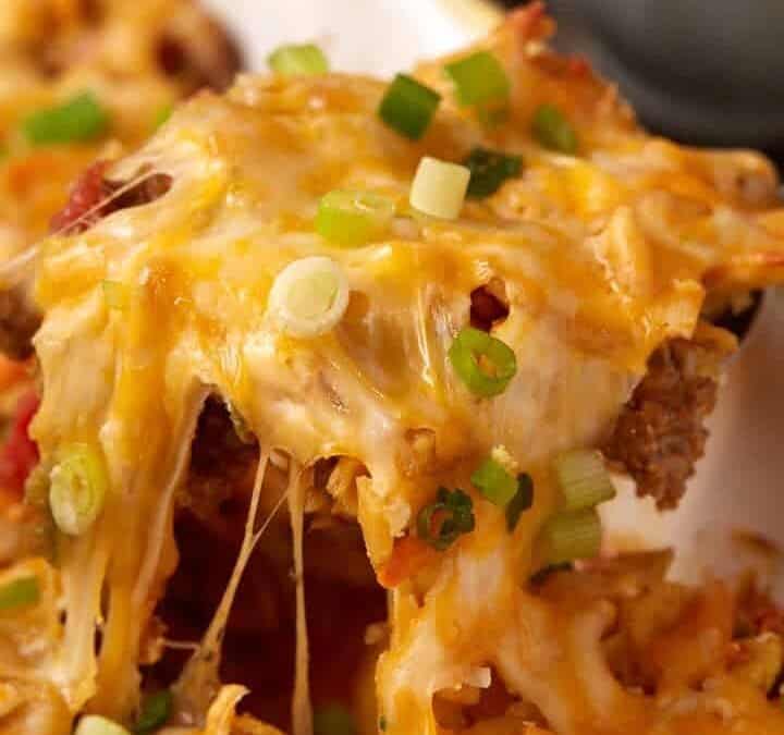 A cheesy spoon full of taco casserole with Fritos.