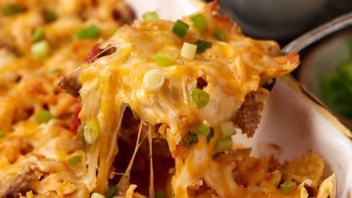 A cheesy spoon full of taco casserole with Fritos.