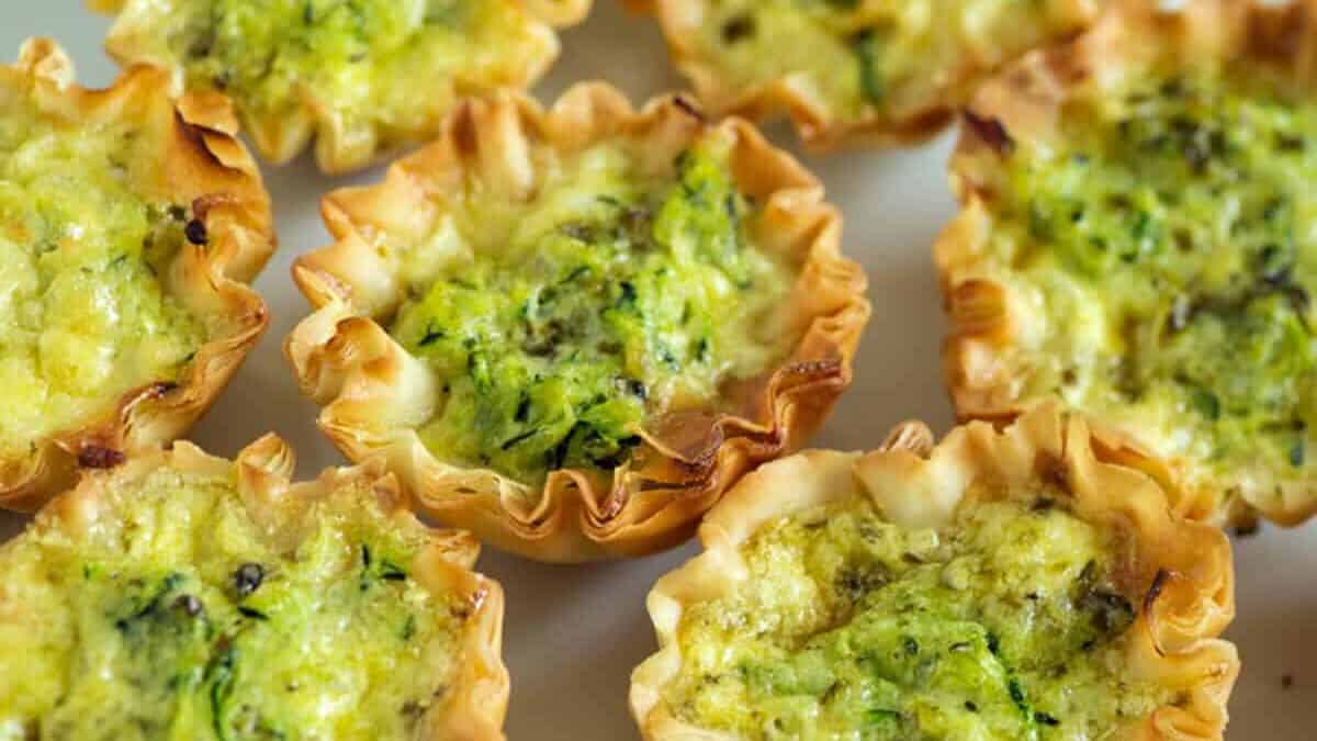 A platter of zucchini quiches with basil leaves.