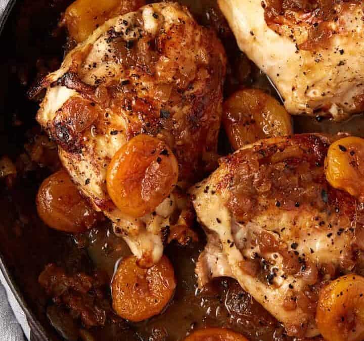 Chicken breasts in a skillet with apricot sauce.