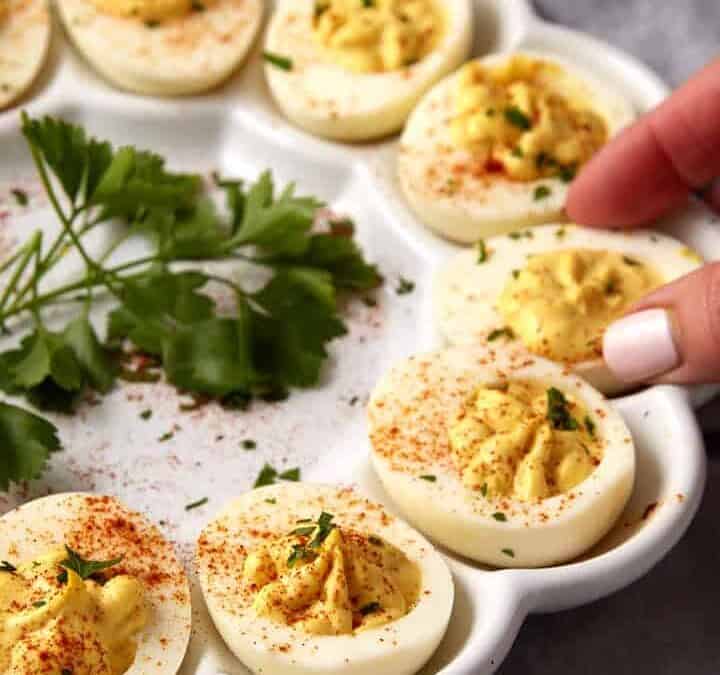 A deviled egg being removed from a platter.