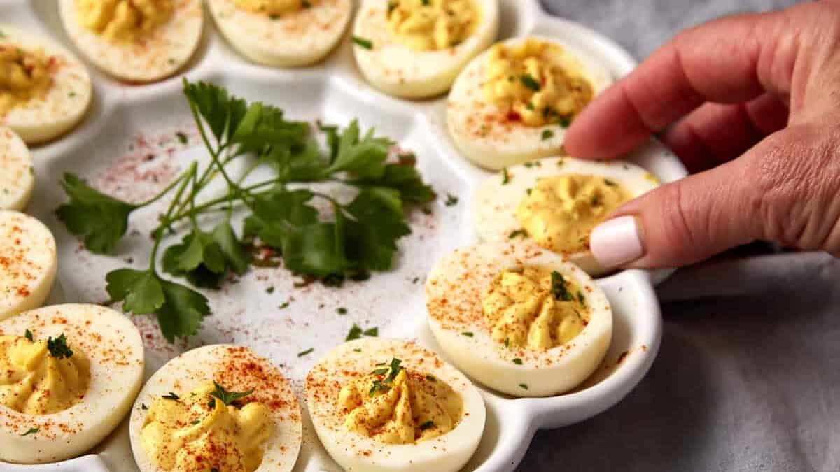A deviled egg being removed from a platter.