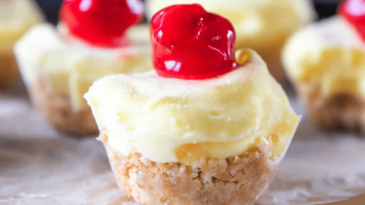 Small cupcakes with cream cheese frosting and a cherry on top.