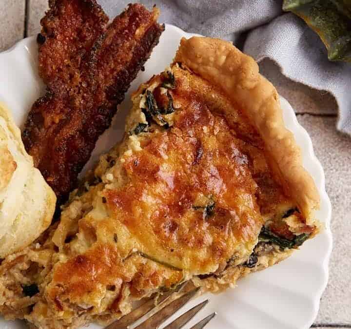 A slice of quiche next to a plate of biscuits.