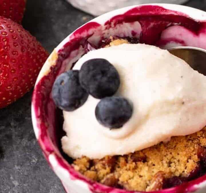 Rhubarb berry crisp in three ramekins with strawberries on the side.