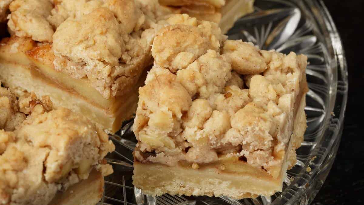 A glass serving platter with apple bars next to serving plates and forks.