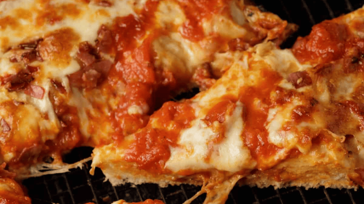 Close-up of cheesy pizza slices topped with tomato sauce and bits of sausage on a thick, golden crust, showing melty cheese and a gooey texture—perfect inspiration for your favorite pizza recipes.