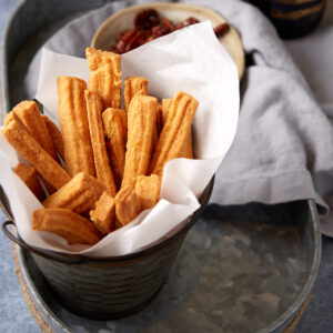 Cheese straws in a basket with parchment paper.