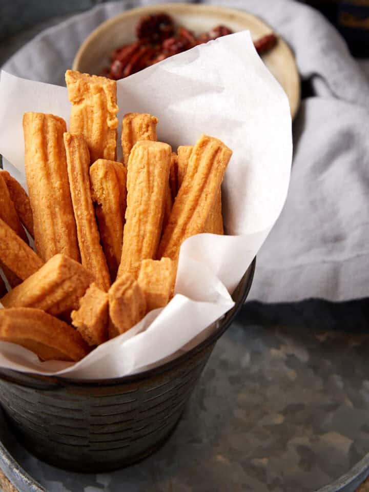 Cheese straws in a basket with parchment paper.