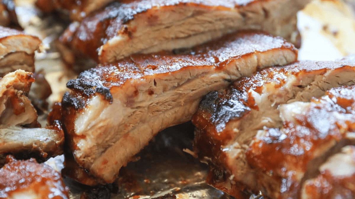 Close-up of juicy, grilled pork ribs with a caramelized barbecue glaze, showing tender meat and a crispy, browned exterior—perfect inspiration for your next crockpot recipes.