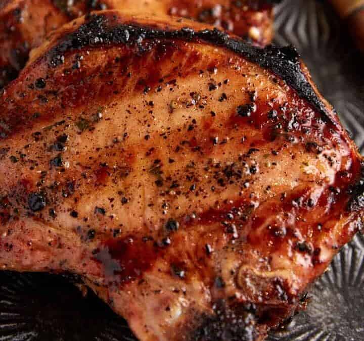 Two grilled pork chops on a metal platter.