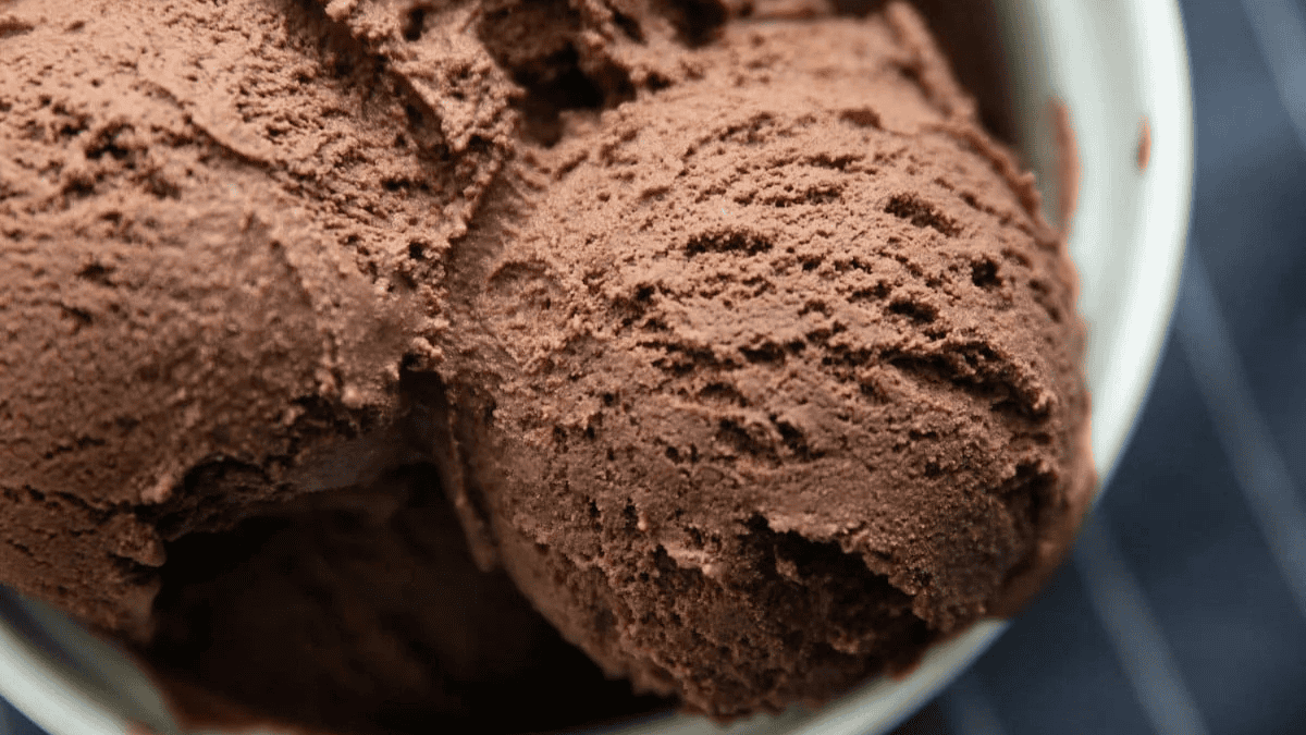 Close-up of several scoops of rich, creamy chocolate ice cream in a white bowl, highlighting a smooth and slightly textured surface—perfect inspiration for your next chocolate recipes.