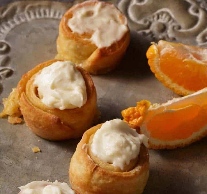 A grey platter with a silver server next to orange rolls.