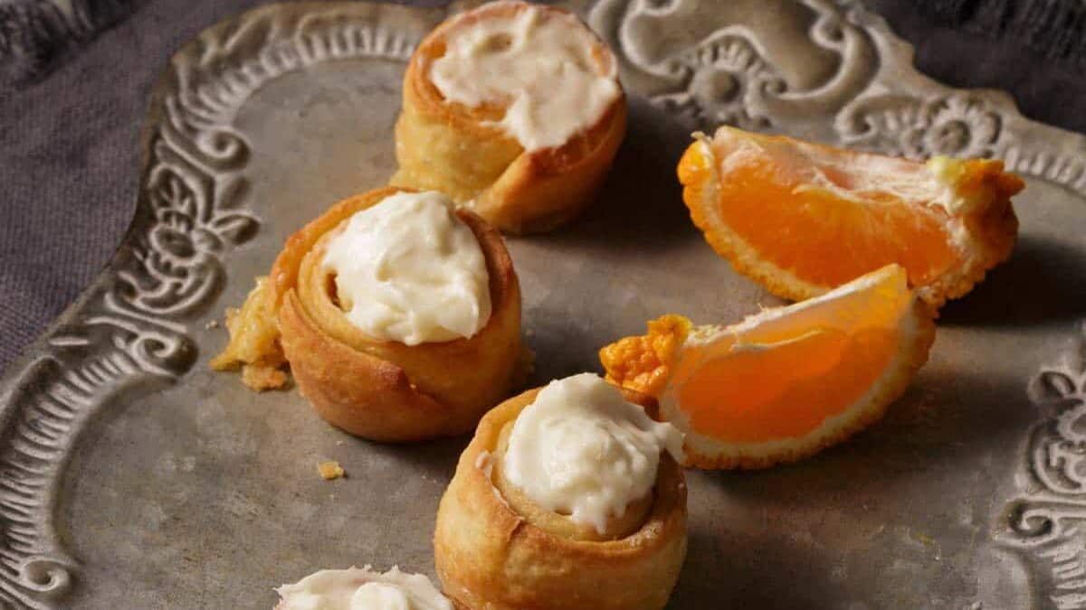 A grey platter with a silver server next to orange rolls.