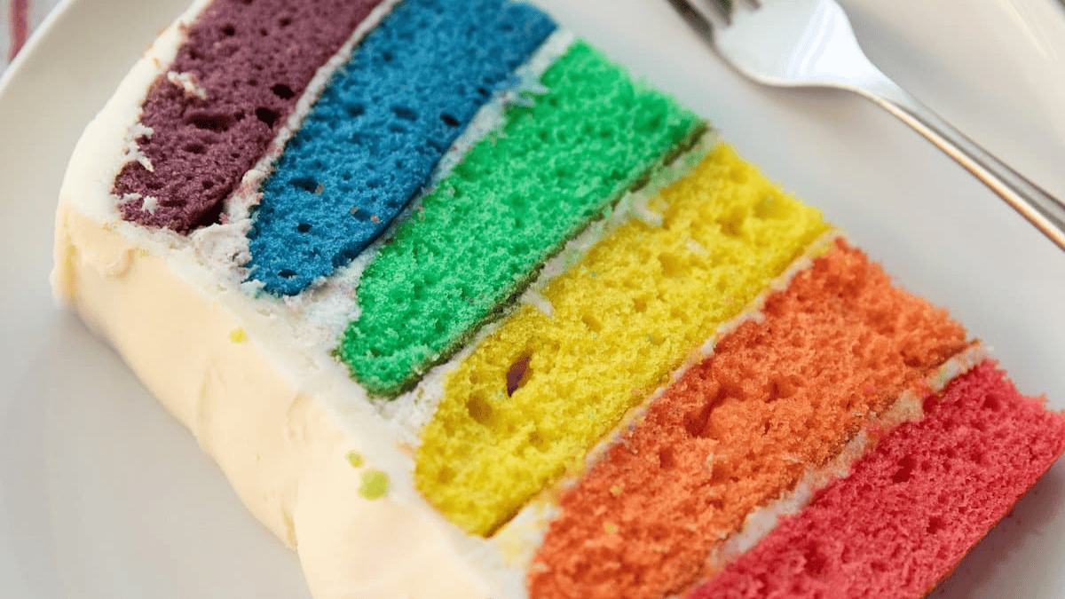 A slice of rainbow cake on a plate.