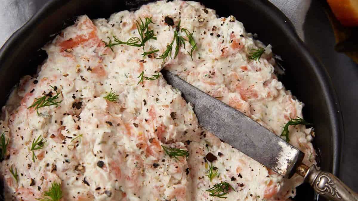 A bowl of salmon dip with a small knife.
