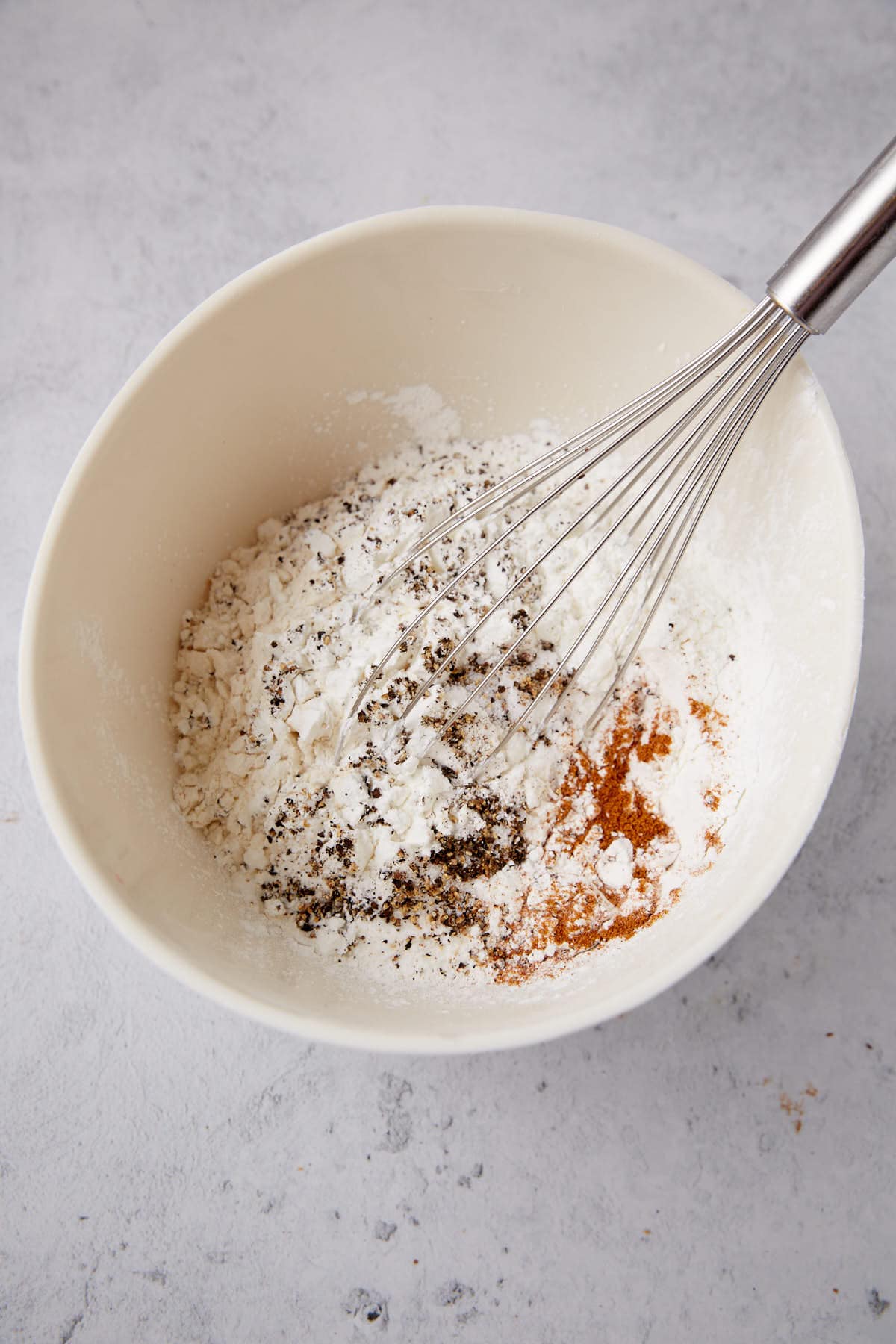 large bowl with flour and seasoning being whisked together