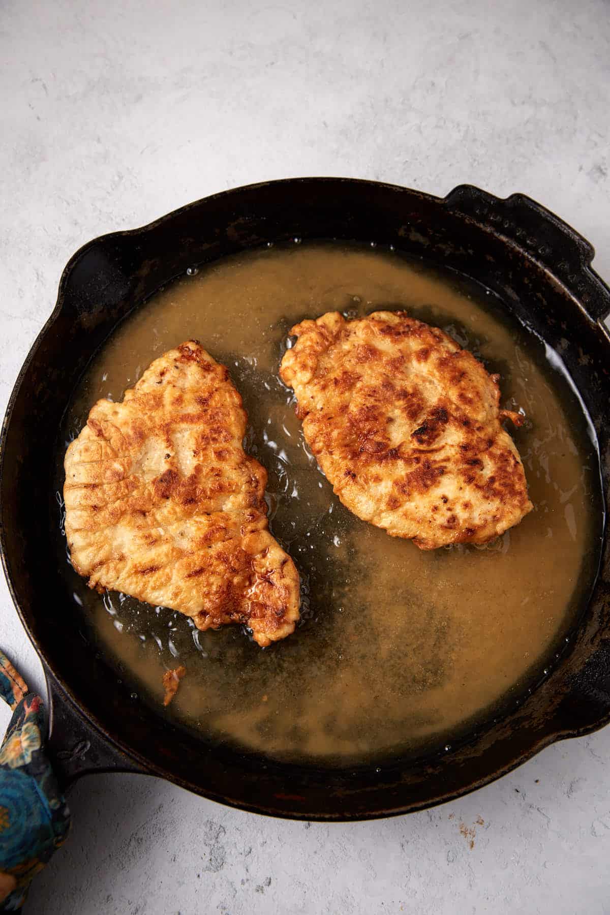 fried chicken sitting inside of a cast iron skillet filled with hot oil