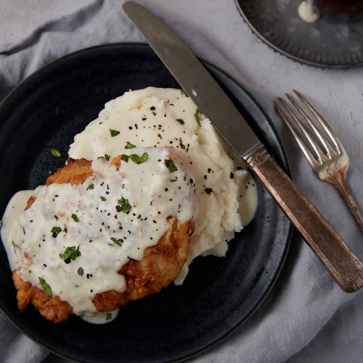 A plate of chicken fried chicken with gravy over mashed potatoes.