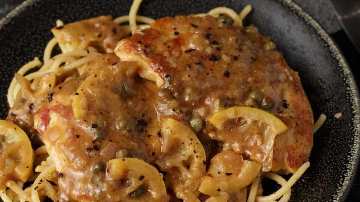 Chicken piccata being served over angel hair pasta