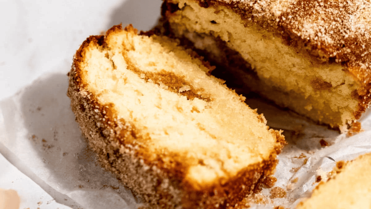 A close-up of a sliced loaf of cinnamon sugar quick bread, showing a golden-brown crust and a soft, moist interior with a visible cinnamon swirl—perfect inspiration for dessert bread recipes.