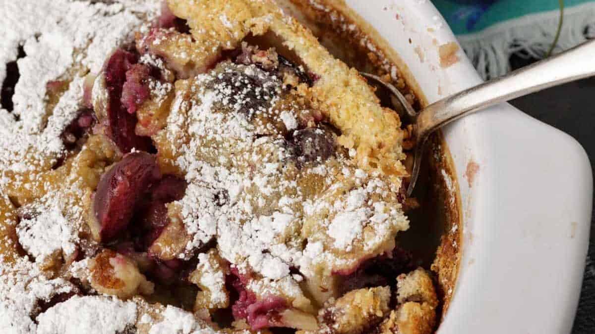 A serving of cherry clafoutis sprinkled with powdered sugar