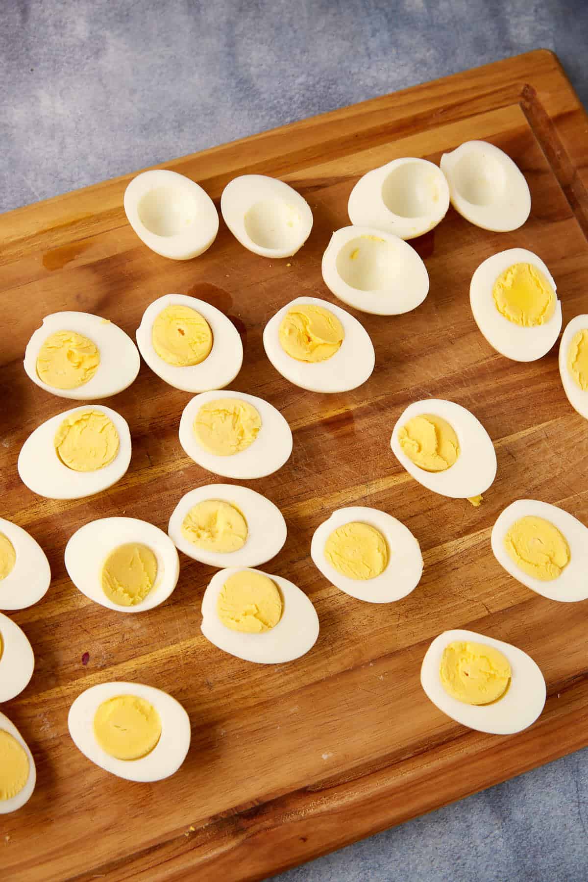 A cutting board with egg halves with the yolk scooped out.