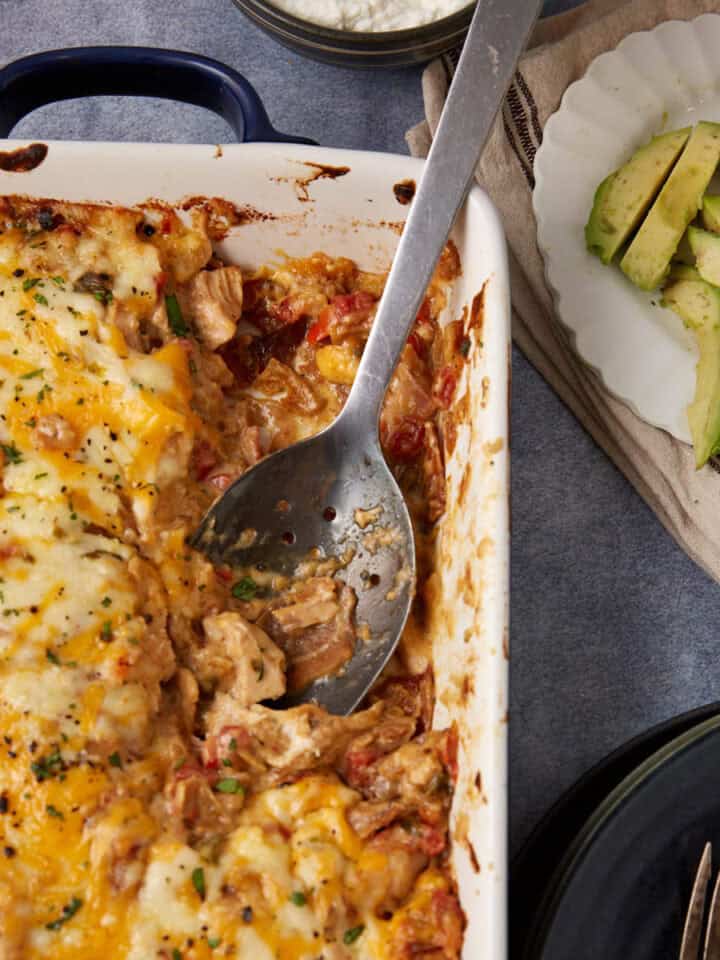 A serving spoon in a casserole dish of king ranch chicken casserole.