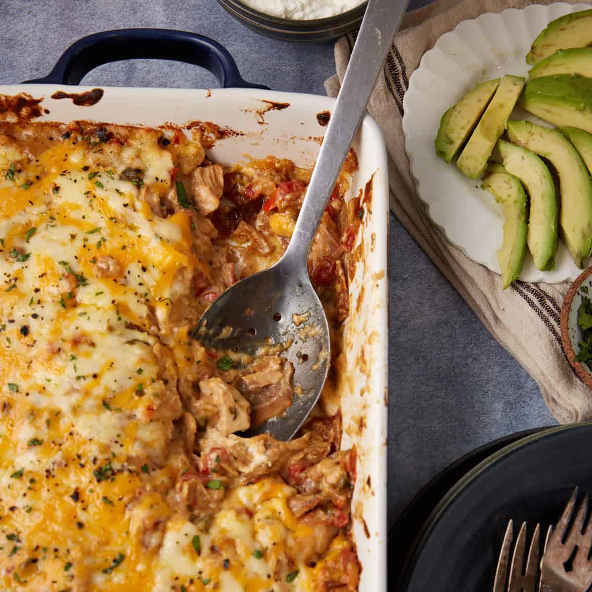 A serving spoon in a casserole dish of king ranch chicken casserole.