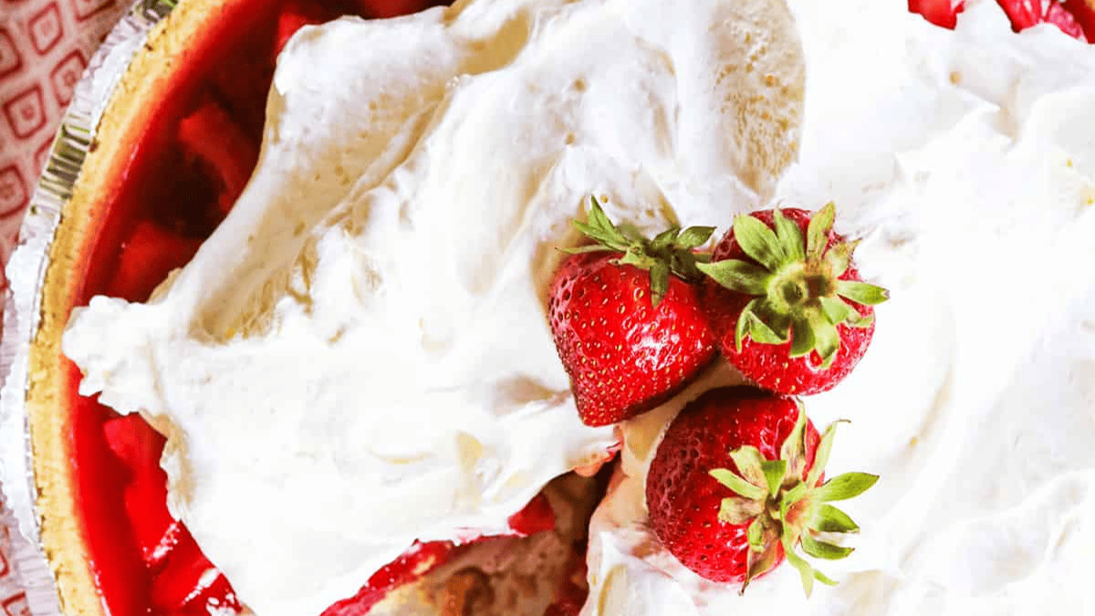 A strawberry pie with whipped cream and strawberries.