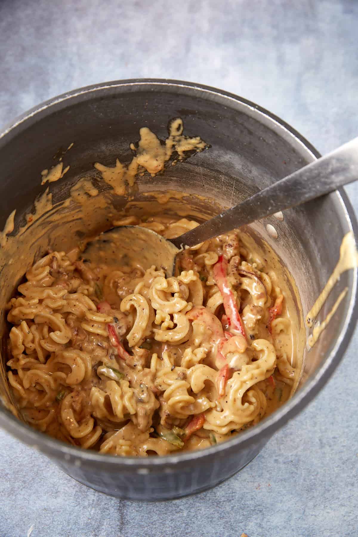 A pot of cooked pasta with the cheese sauce poured over the top.