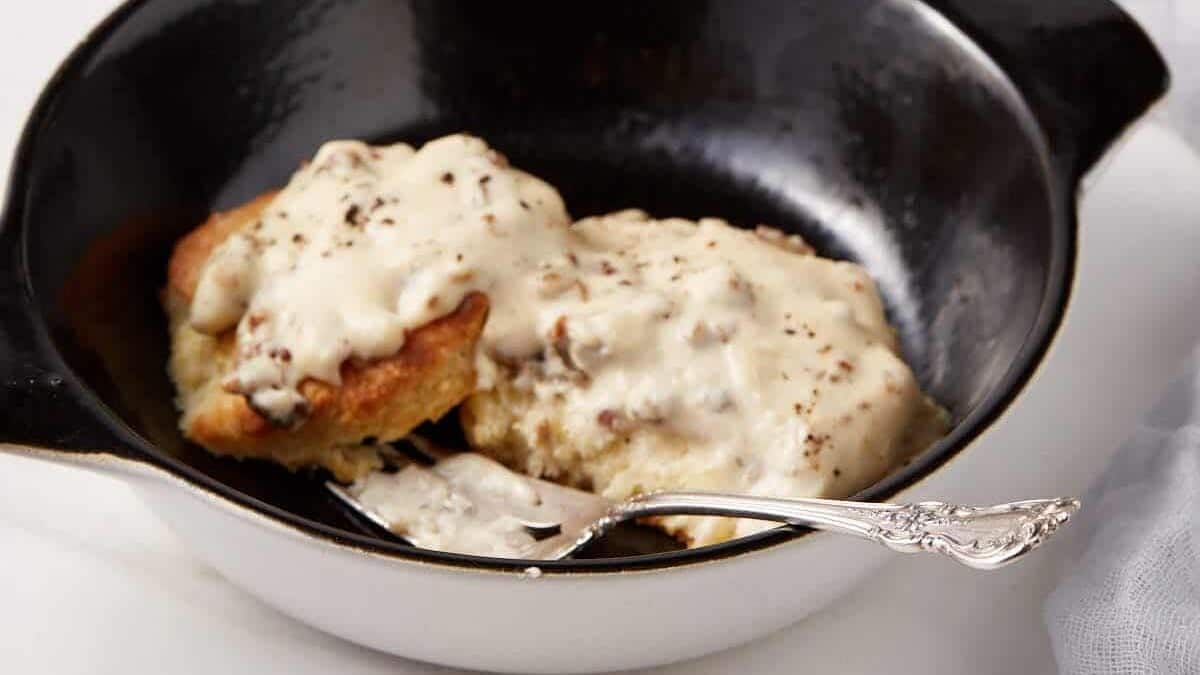 Sausage gravy poured over biscuits in a black casserole dish.