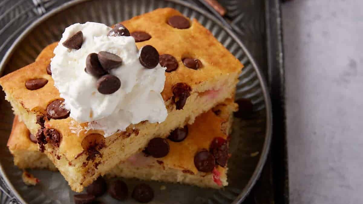 Two chocolate chip pancakes with whipped cream on top.