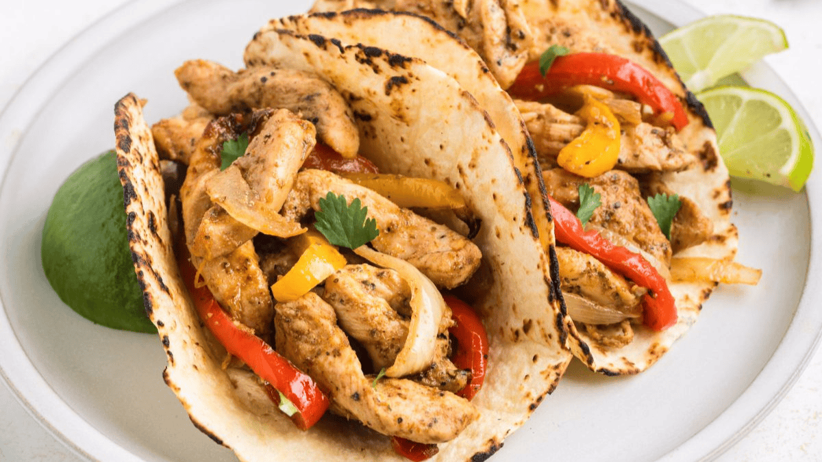 Two tacos with chicken and peppers on a plate