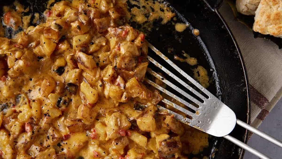 Breakfast potatoes in a skillet next to biscuits.